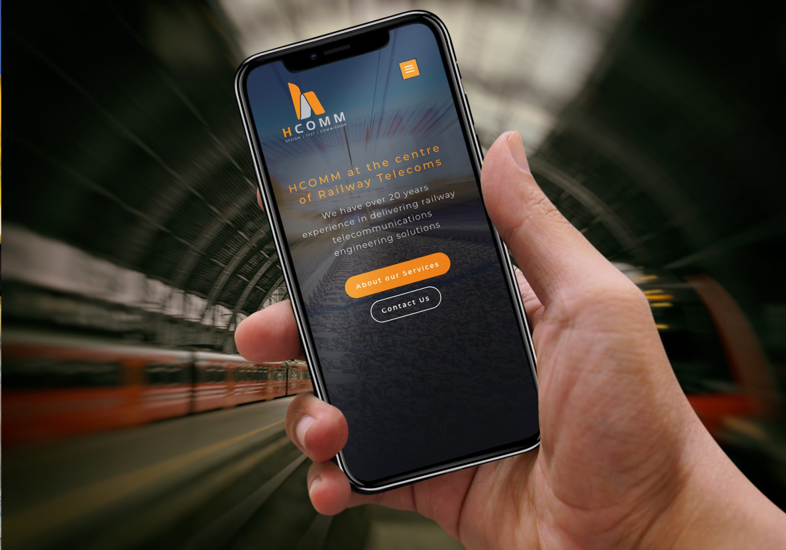 Hcomm's new website on a mobile phone with trains in the background